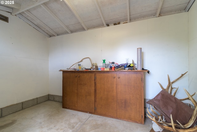 bar area featuring concrete flooring and vaulted ceiling