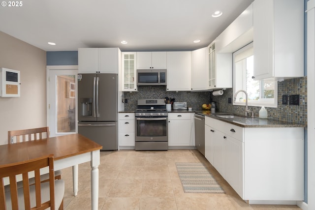 kitchen featuring stainless steel appliances, a sink, backsplash, white cabinets, and recessed lighting