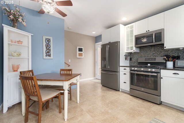kitchen with stainless steel appliances, ceiling fan, dark countertops, backsplash, and white cabinets