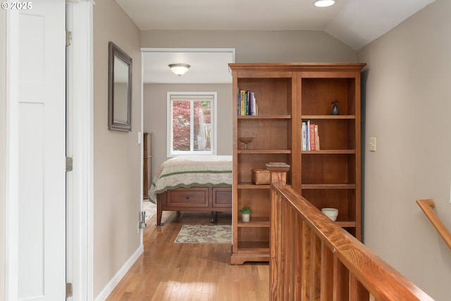 hallway featuring light wood-type flooring, baseboards, and lofted ceiling