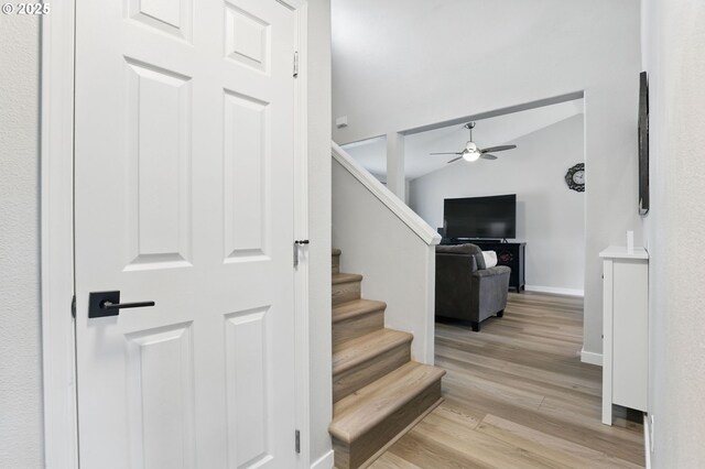 staircase with a ceiling fan, wood finished floors, and baseboards