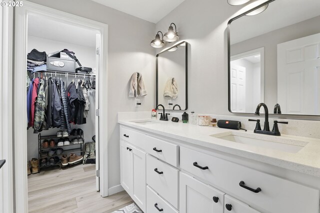 full bath featuring wood finished floors, double vanity, and a spacious closet
