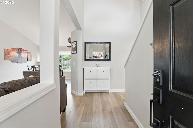 hall featuring light wood-style flooring and baseboards