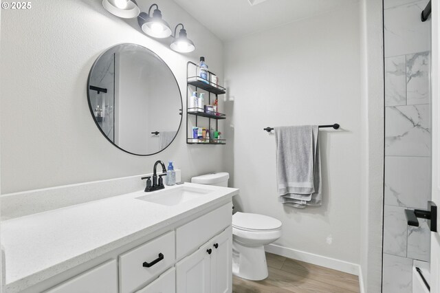 bathroom featuring toilet, vanity, wood finished floors, and baseboards