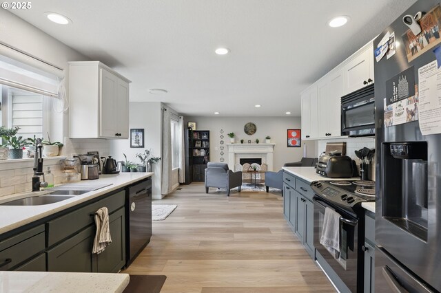 kitchen with black appliances, a sink, backsplash, light countertops, and recessed lighting
