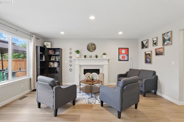 living room featuring light wood-style floors, recessed lighting, a fireplace, and baseboards