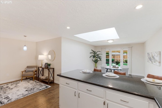 180 Nelson Ln, Gladstone, OR 97027 - kitchen featuring a skylight, dark countertops, dark wood-style flooring, white cabinetry, and a textured ceiling