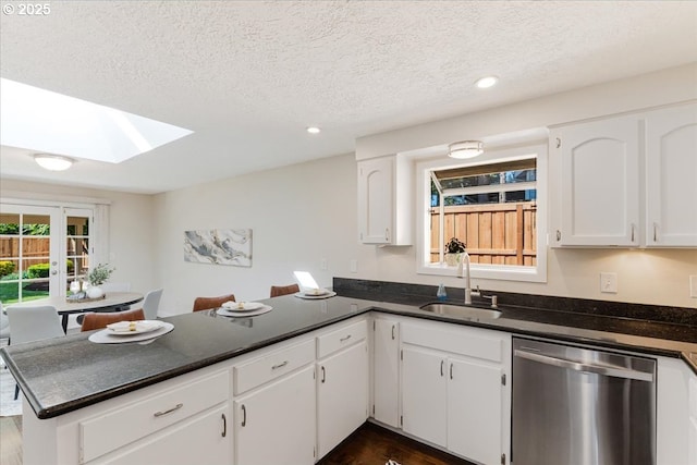 180 Nelson Ln, Gladstone, OR 97027 - kitchen with stainless steel dishwasher, a sink, a skylight, a peninsula, and dark countertops