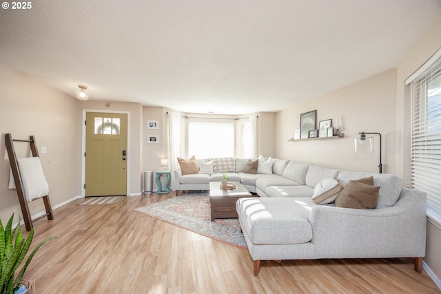 living room with plenty of natural light, a textured ceiling, and light hardwood / wood-style flooring