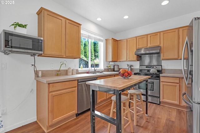 16085 SW Towhee Ln, Beaverton, OR 97007 - kitchen featuring stainless steel appliances, a sink, under cabinet range hood, recessed lighting, and light countertops