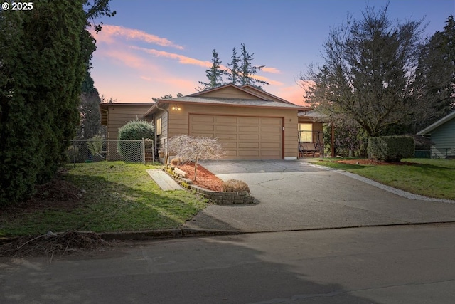 ranch-style home featuring a front lawn, an attached garage, driveway, and fence