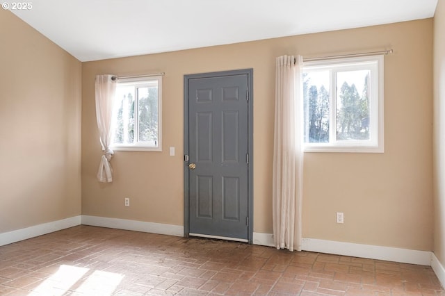 entryway featuring brick floor and baseboards