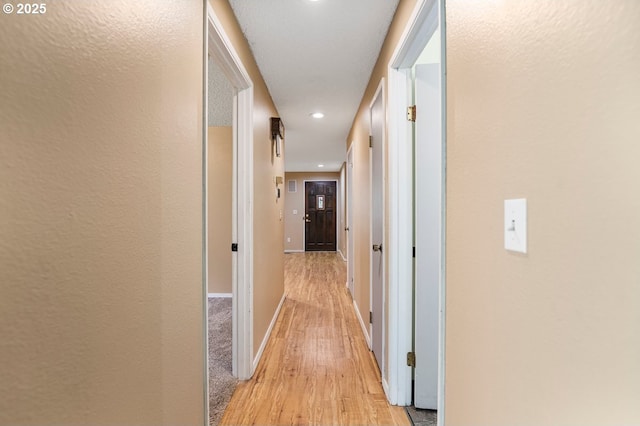 hall featuring light wood-style flooring, recessed lighting, and baseboards