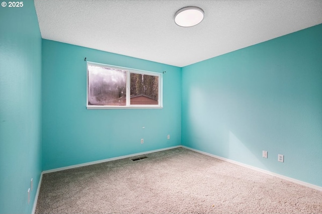 spare room with baseboards, carpet flooring, a textured ceiling, and visible vents