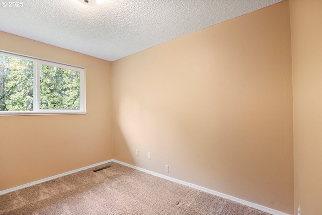 carpeted empty room with visible vents, a textured ceiling, and baseboards