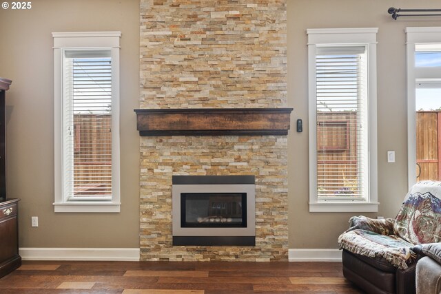 living room with wood finished floors, baseboards, and a glass covered fireplace