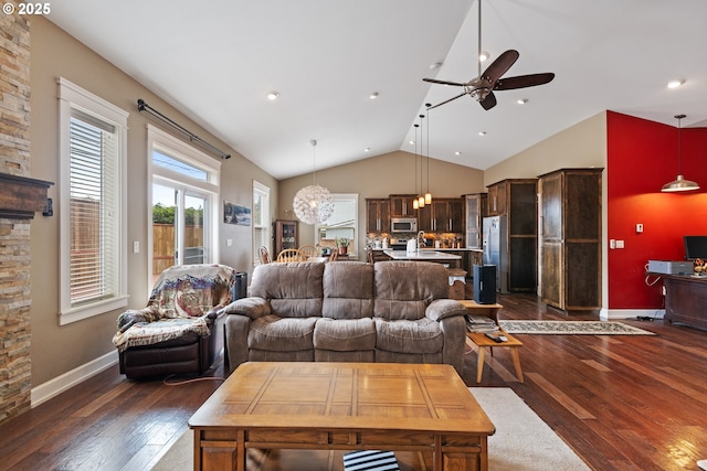 living area featuring dark wood-style flooring, a ceiling fan, lofted ceiling, baseboards, and a chandelier