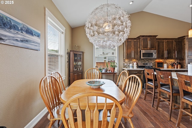 dining space featuring dark wood-type flooring, vaulted ceiling, a chandelier, and baseboards