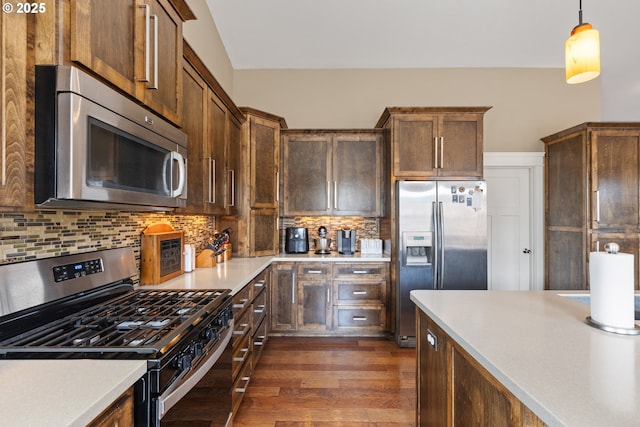 kitchen with appliances with stainless steel finishes, light countertops, dark wood finished floors, backsplash, and decorative light fixtures