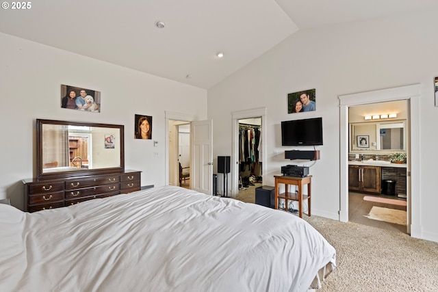bedroom with vaulted ceiling, carpet, a walk in closet, a closet, and connected bathroom