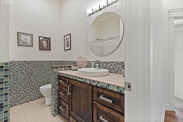bathroom with toilet, vanity, a wainscoted wall, and tile patterned floors