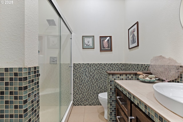 full bathroom featuring a shower stall, tile walls, tile patterned floors, vanity, and toilet