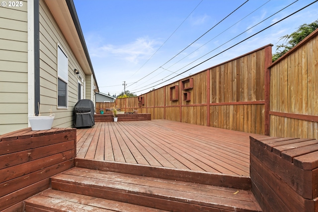 wooden deck with a fenced backyard and area for grilling