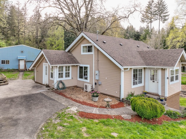 view of front of property featuring ac unit, roof with shingles, and aphalt driveway