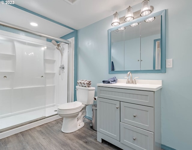 full bathroom featuring a stall shower, wood finished floors, vanity, baseboards, and toilet