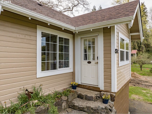 view of exterior entry with a shingled roof