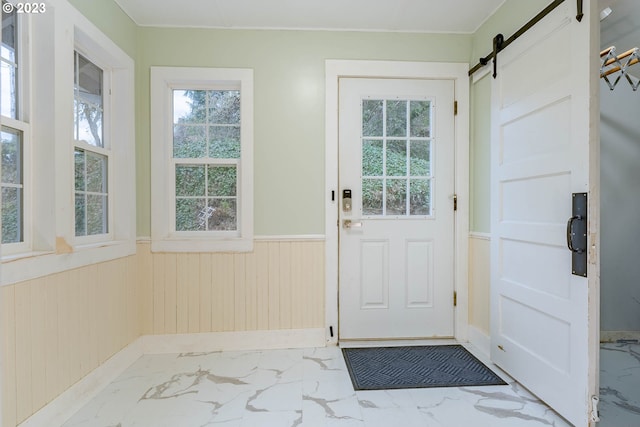 entryway with a barn door, marble finish floor, wainscoting, and a wealth of natural light
