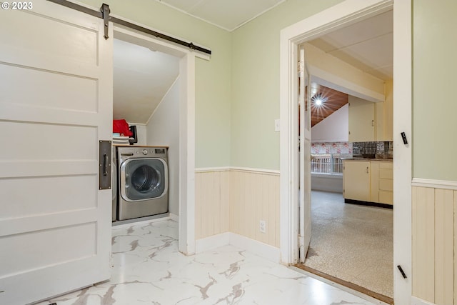laundry area featuring washer / dryer, a wainscoted wall, a barn door, and marble finish floor