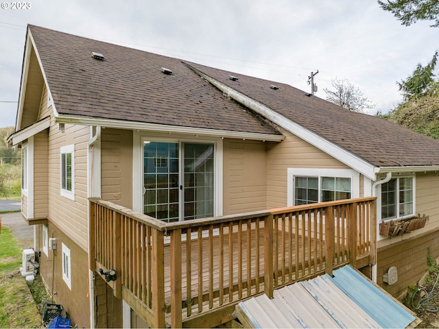 rear view of property featuring a wooden deck and a shingled roof