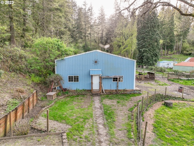 view of outdoor structure featuring a view of trees, fence, and entry steps