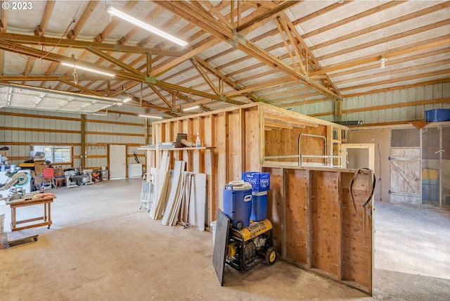 misc room with a garage, concrete flooring, and vaulted ceiling