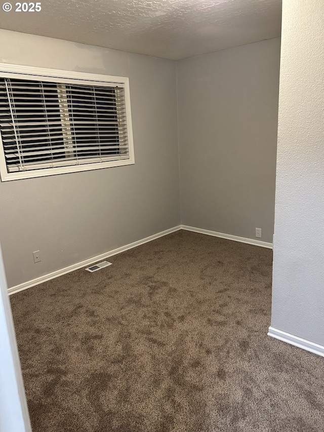 carpeted spare room featuring visible vents, a textured ceiling, and baseboards