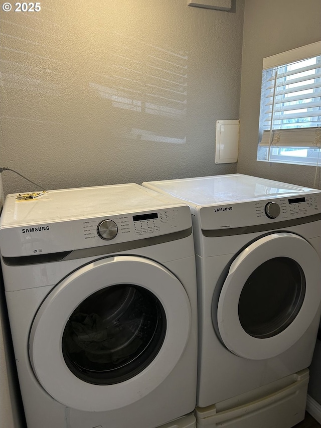 laundry area featuring washing machine and dryer, laundry area, and a textured wall