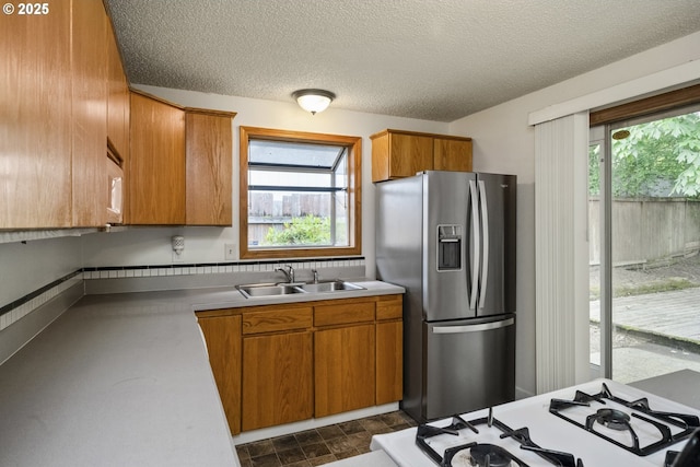 730 SW Dolph St, Portland, OR 97219 - kitchen with stainless steel refrigerator with ice dispenser, brown cabinetry, light countertops, a textured ceiling, and stone finish flooring
