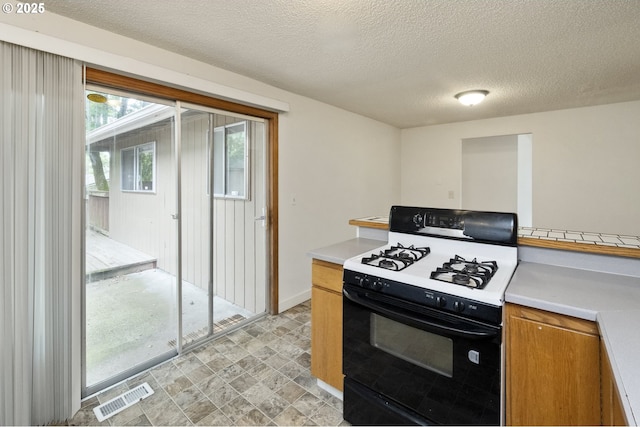 730 SW Dolph St, Portland, OR 97219 - kitchen featuring range with gas cooktop, light countertops, brown cabinets, stone finish flooring, and a textured ceiling