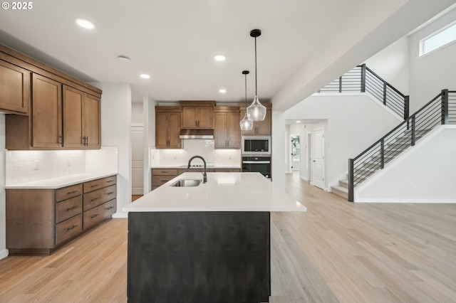 4321 N 11th Way, Ridgefield, WA 98642 - kitchen with black oven, built in microwave, under cabinet range hood, brown cabinetry, and light wood-style flooring