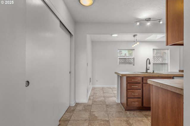 6125 S Hood Ave, Portland, OR 97239 - kitchen with brown cabinetry, baseboards, light tile patterned flooring, a sink, and light countertops