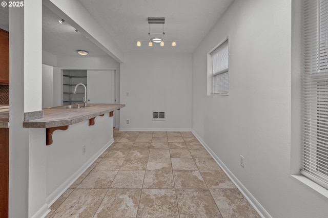 6125 S Hood Ave, Portland, OR 97239 - kitchen with light tile patterned floors, baseboards, visible vents, a breakfast bar, and a sink