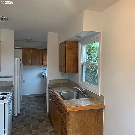 6125 S Hood Ave, Portland, OR 97239 - kitchen featuring a sink, white appliances, and brown cabinets