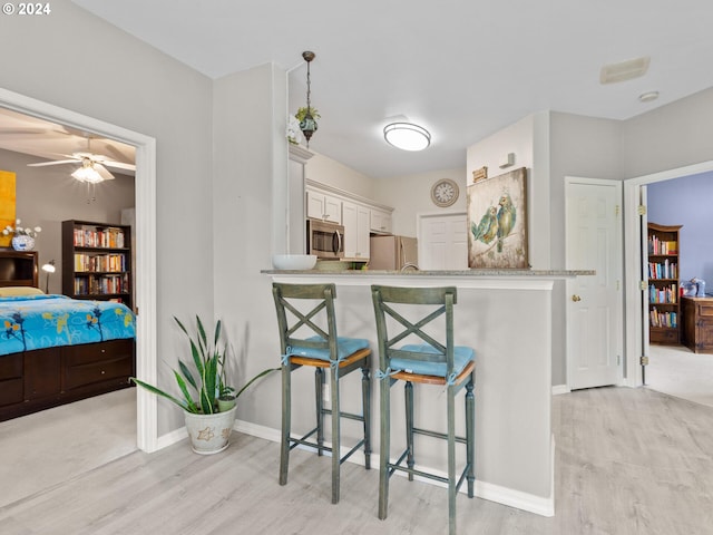 1170 NE 64th Ln Unit 1209, Hillsboro, OR 97124 - kitchen featuring appliances with stainless steel finishes, light wood-style flooring, a kitchen breakfast bar, white cabinets, and a ceiling fan