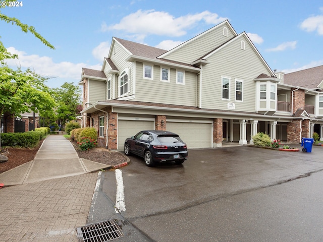 1170 NE 64th Ln Unit 1209, Hillsboro, OR 97124 - view of property featuring brick siding, driveway, an attached garage, and roof with shingles