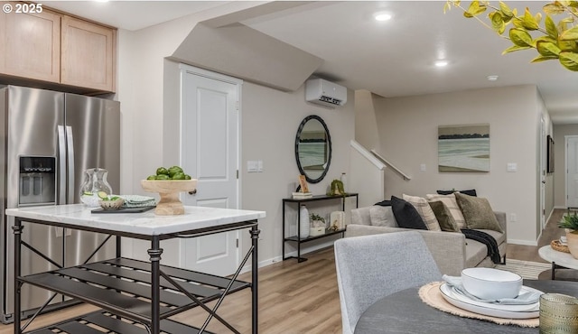 dining area featuring a wall unit AC, light wood-type flooring, baseboards, recessed lighting, and stairs