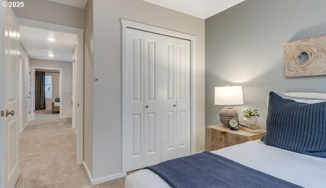 bedroom with light colored carpet, a closet, and baseboards