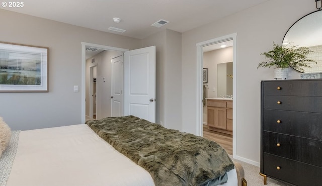 bedroom with baseboards, connected bathroom, light colored carpet, and a sink