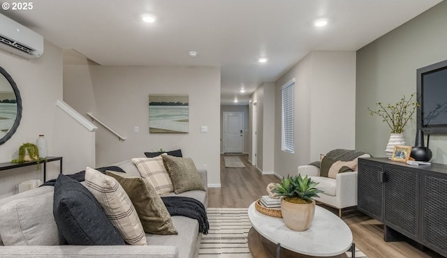 living area featuring light wood-type flooring, a wall mounted AC, recessed lighting, and baseboards