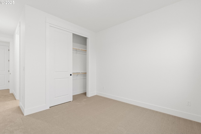 unfurnished bedroom featuring light colored carpet and a closet